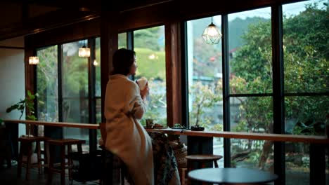 woman enjoying a drink at a cozy cafe with a view