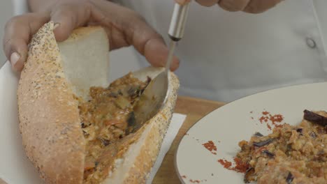 a large loaf of bread is being smeared with a vegetable stuffing