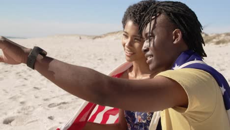 pareja envuelta en bandera estadounidense sentada juntos en la playa 4k