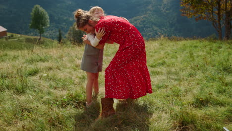 happy woman daughter hugging on green meadow. mother with girl enjoying holiday