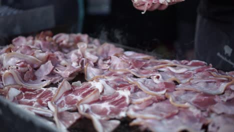slowmo - close up food truck man putting bacon on a grill