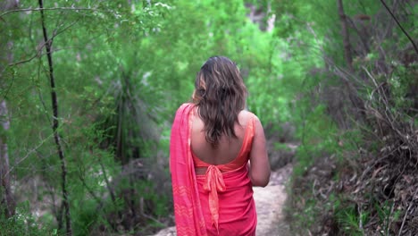 the rear of a beautiful indian woman in a red sari walking through the wilderness of the blue mountains, nsw, australia - slow motion