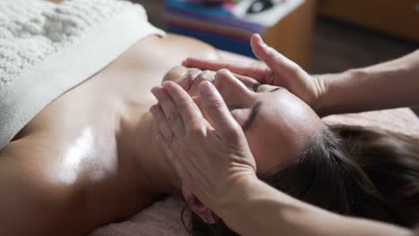 masseur rubbing face of resting patient in spa center