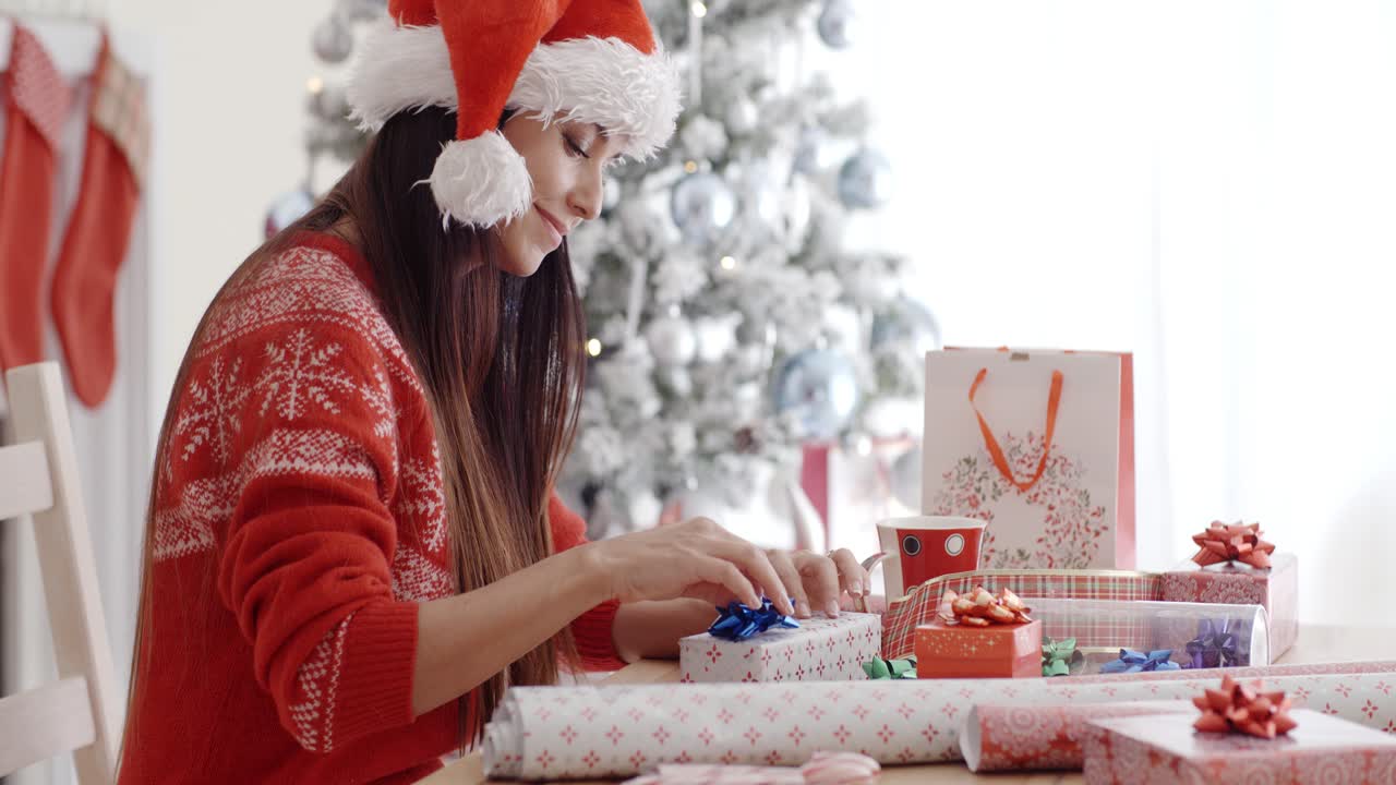una mujer joven sentada envolviendo regalos de navidad.