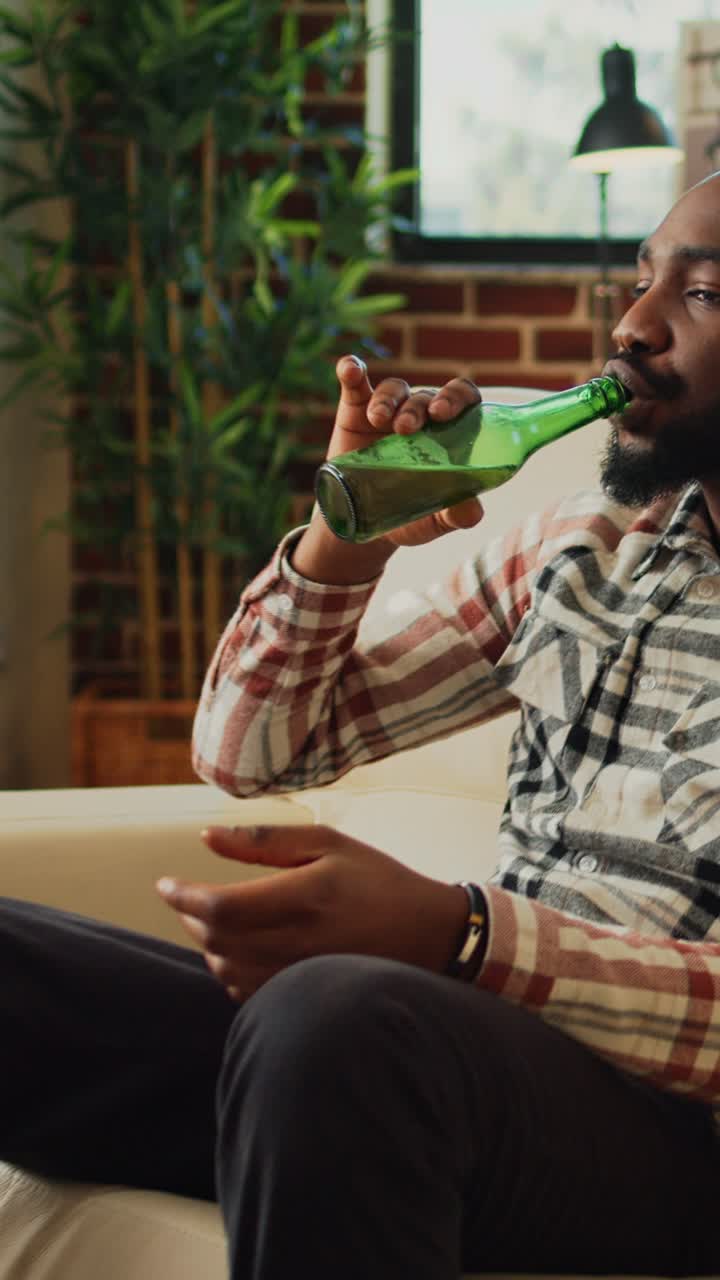 Vertical video: Cheerful adult taking bite of pizza at home