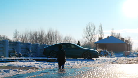 rear view of the little toddler boy wearing black clothes and cap. baby boy walks outdoors in winter in the yard.