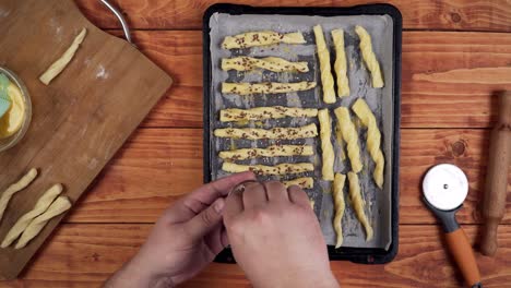 Sprinkling-sesame-seeds-on-top-of-sweet-baked-dough-sticks