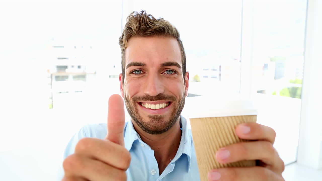 hombre de negocios tomando un café y dando pulgares hacia arriba