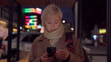 mujer usando teléfono móvil en la calle nocturna