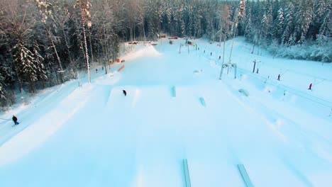 Tracking-aerial-view-of-a-snowboarder-doing-360-jump-in-a-terrain-park