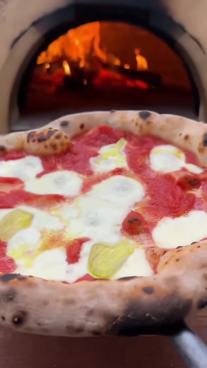 Pizza napoletana appena sfornata guarnita con basilico da forno a legna