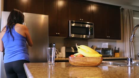 push in shot, female coming into frame to get orange juice out of refrigerator, then pours juice into glass