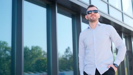 portrait of a young smiling man standing on the street near an modern office building. head shot