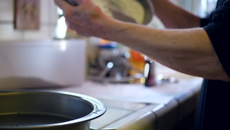 un chef cubriendo sartenes redondas con harina para funcionar como una superficie no pegajosa mientras hornea pastel de chocolate vegano para el postre