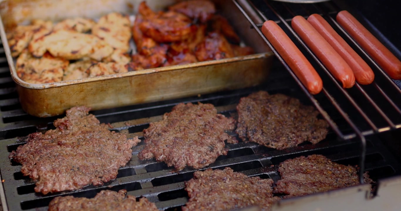 Barbecue del 4 luglio. Griglia nera che cucina carne, pollo, manzo, hot dog, cipolle in celebrazione del 250° compleanno degli Stati Uniti d'America. In Cinema 4K 30fps rallentato da 120fps