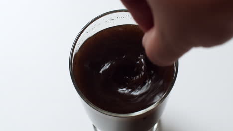 stirring a glass of cold brew dark americano coffee clockwise