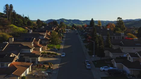 aerial over beautiful suburban neighborhood as two suvs pull out of driveway of one of the homes.