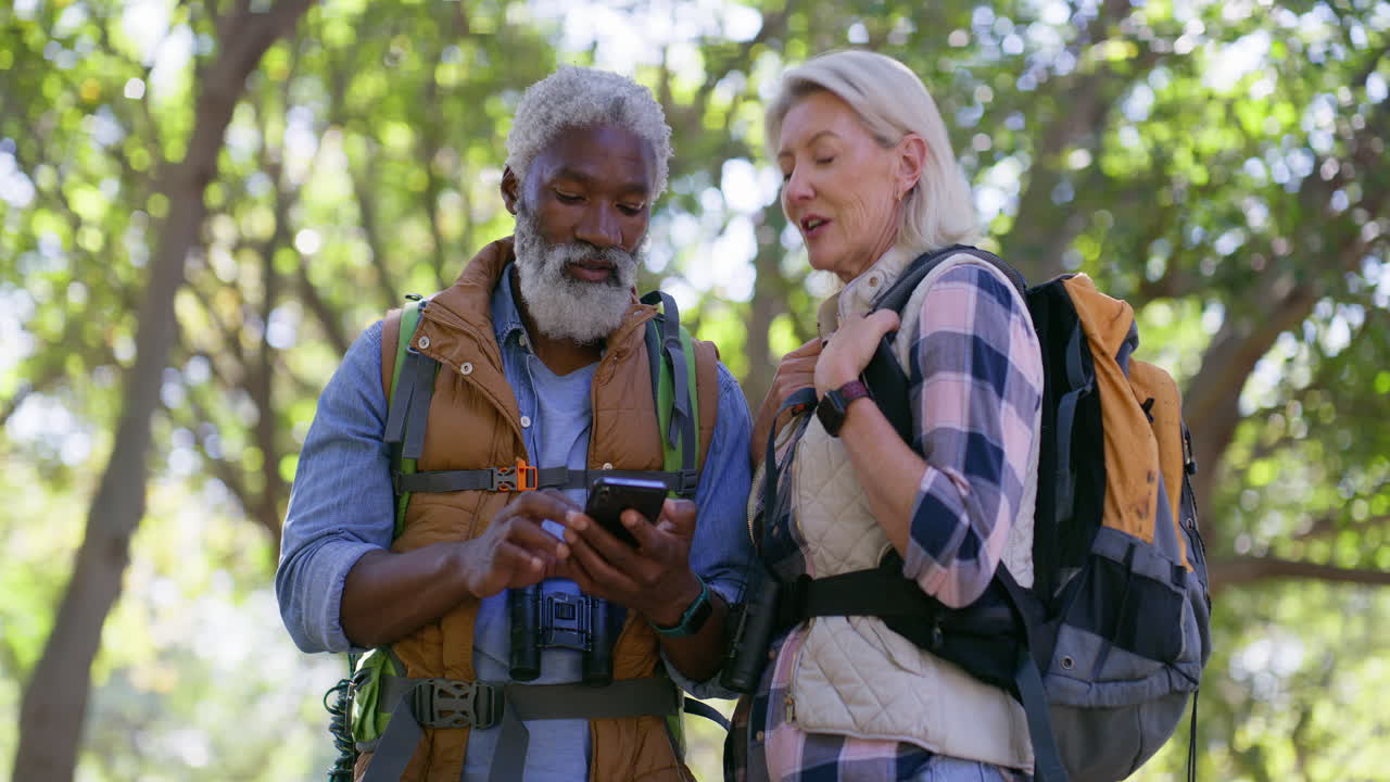 Mature Couple Hiking in Forest Using Mobile Phone