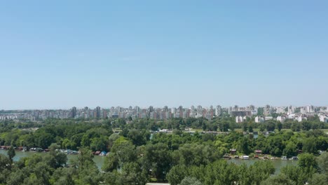 Antena:-Horizonte-De-La-Ciudad-De-Belgrado-En-El-Día-De-Verano,-Vista-Sobre-Ada-Ciganlija-En-Serbia