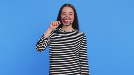 happy smiling young woman holding magnifier glass on teeth health care hygiene stomatology concept