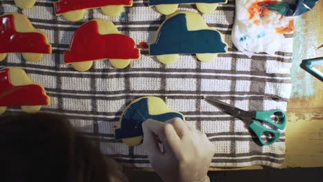 woman decorates homemade vehicle shaped cookies with sugar icing