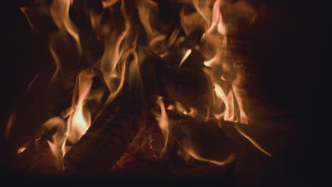 Charred-fire-logs-with-glowing-embers-and-hot-dancing-flames-in-stove-burner