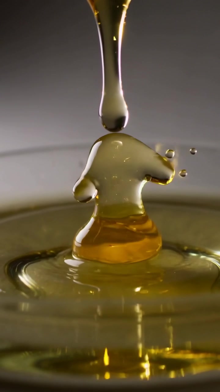 Video verticale: Beccuccio che rilascia una goccia di miele che si scontra con un piatto in studio, formando una cupola per studio