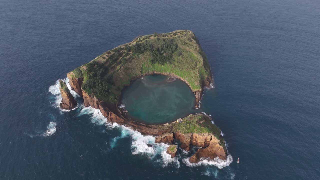 Small coastal island in the atlantic ocean, cliffs and small bay lake in the middle. Aerial drone video.