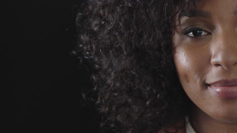 portrait of attractive african american woman smiling looking at camera black female beauty isolated on black background half face