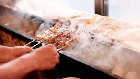 cooking skewered meat on a smoky grill