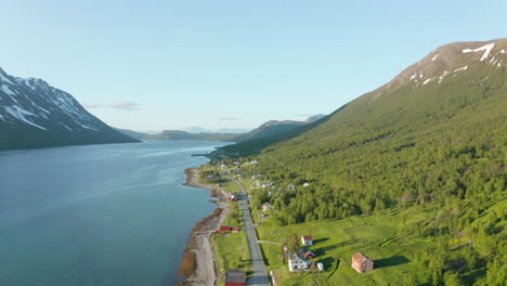 Vista-Aérea-De-Casas,-Una-Carretera-Y-Un-Pueblo,-En-La-Costa-Del-Océano-ártico,-En-Medio-De-Fiordos-Y-Montañas,-Soleado,-Día-De-Verano,-En-Rotsund,-Troms,-Nordland,-Noruega---Descendiendo,-Disparo-De-Drones