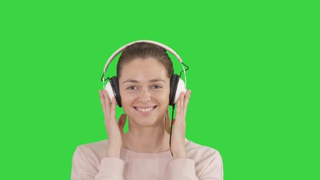 a young woman listening to music in headphones on a green screen, chroma key