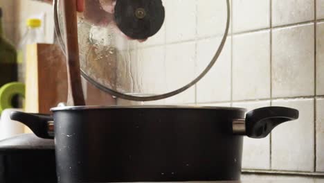 close up on man's hands, open a pot's lid and stiiring food with a wooden spoon, side view static shot 120fps