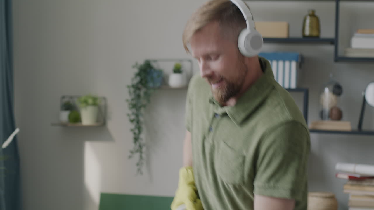 Man Cleaning House with a Mop while Listening to Music