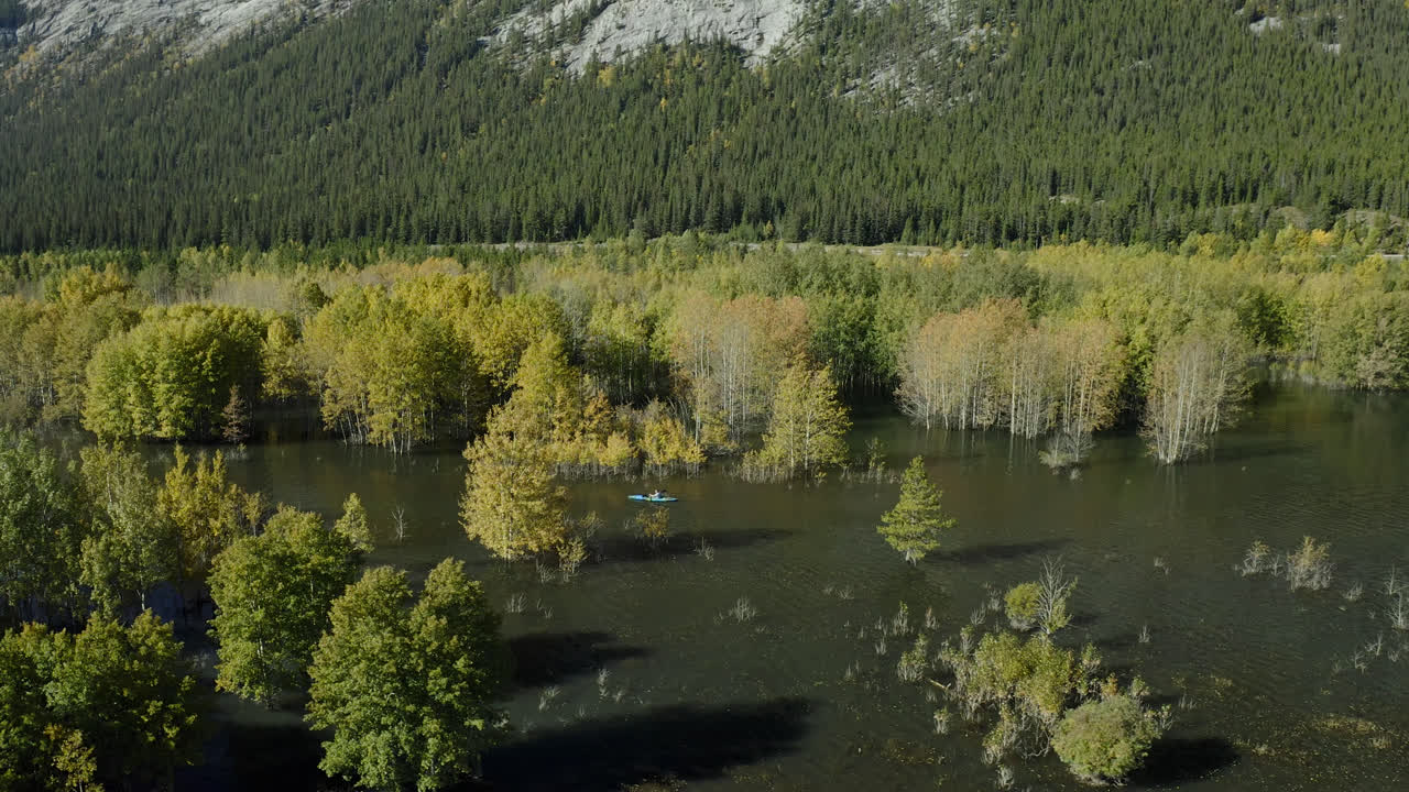 Kayaker Paddling Through Fall Colors On Abraham Lake In Alberta, Canada