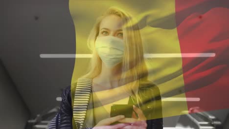 Animation-of-flag-of-belgium-waving-over-woman-wearing-face-mask-during-covid-19-pandemic