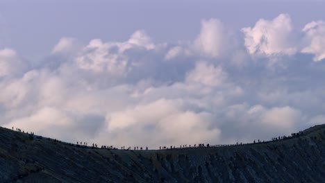 tourists walking on the edge of the crater volcano of mount ijen, banyuwangi, east java, indonesia.