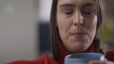 primer plano de una feliz mujer caucásica bebiendo café y sonriendo