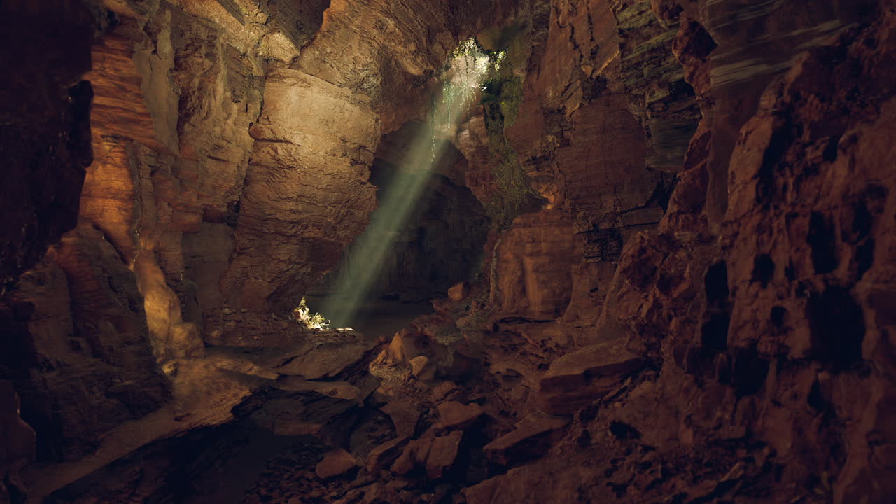 un haz de luz brilla a través de la entrada de una cueva oscura