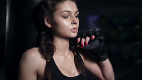 Tired-female-boxer-resting-laying-down-on-the-punching-bag.-Shot-in-4k