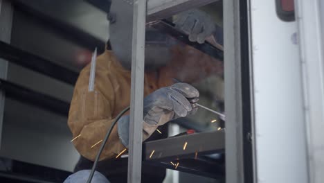 welder using stick welder on metalwork frame in delivery vehicle