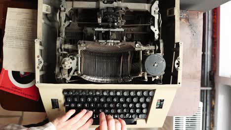 overhead view of a person typing on antique manual typewriter