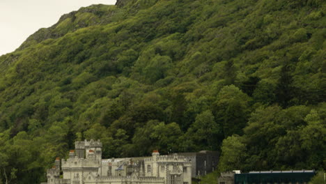 Tilt-down-Reveal-Of-Kylemore-Abbey-And-Victorian-Walled-Garden-By-The-Waterside-In-Galway,-Ireland