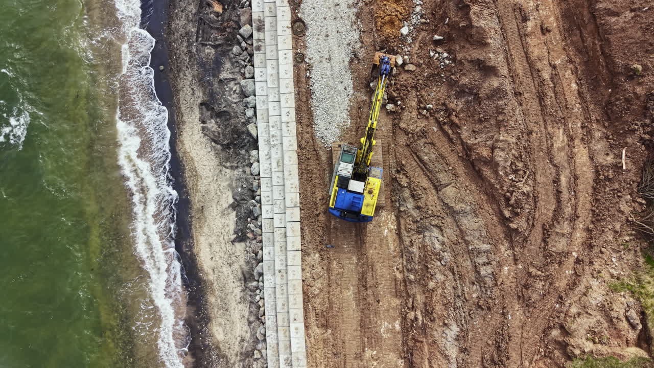Costruzione di un muraglione lungo la costa per proteggere la terra dall'erosione vicino a una zona balneare durante il giorno.