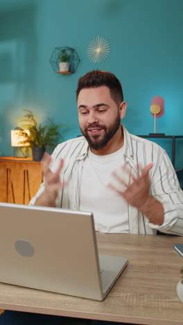 man looking at laptop screen making video webcam conference call with friends or family at home