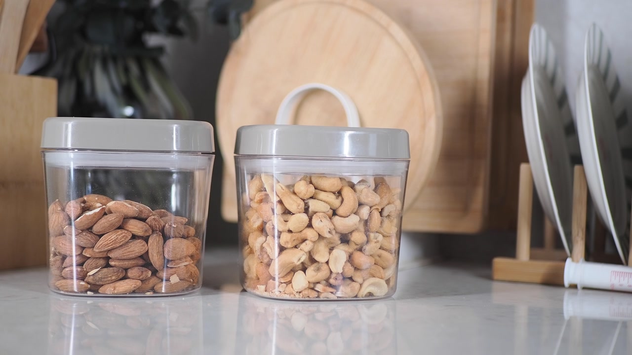 Clear Containers of Almonds and Cashews on a Kitchen Counter