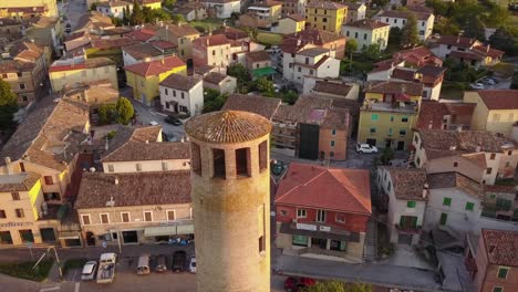 Vista-De-Drones-De-Una-Torre-Histórica-En-Un-Pequeño-Pueblo-Durante-Una-Puesta-De-Sol