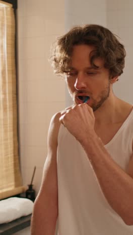 man brushing teeth in bathroom