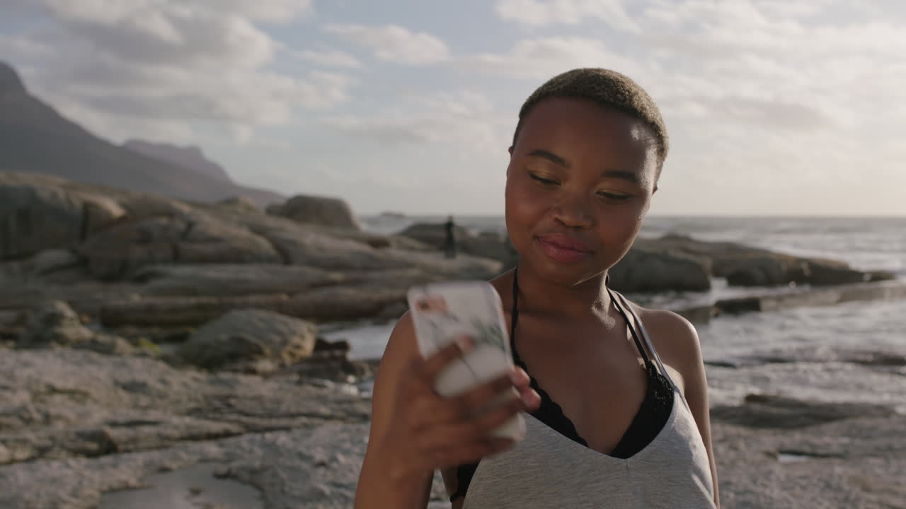 young happy african american woman taking funny selfie photo at beach using smartphone