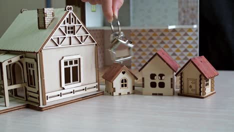 keychain with house keys in hand. toy houses on the table. purchase of real estate. real estate transaction